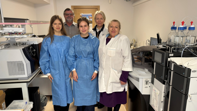 Pieci laboratorijas darbinieki halātos atrodas laboratorijas telpās