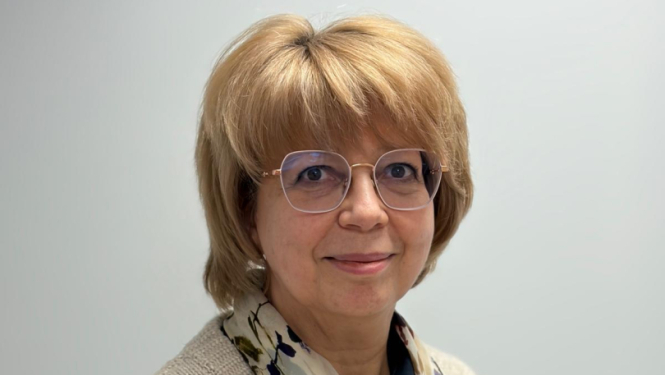 Sieviete stāv un smaida, balta siena fonā