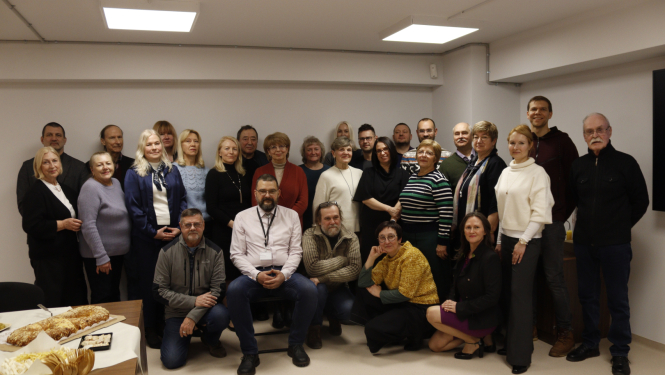 Darba kolektīva kopbilde kabinetā ar baltām sienām