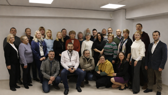 Darba kolektiva kopbilde, fonā balta siena