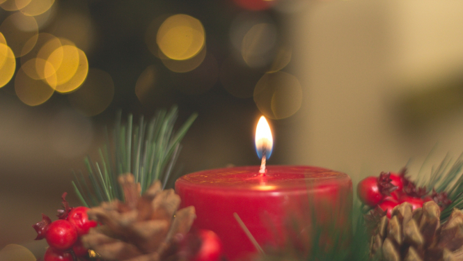 Sarkana degoša svece ar egles zariem apkārt,  čiekuriem un sarkanām ogām