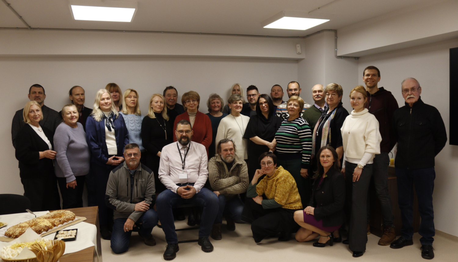 Darba kolektīva kopbilde kabinetā ar baltām sienām