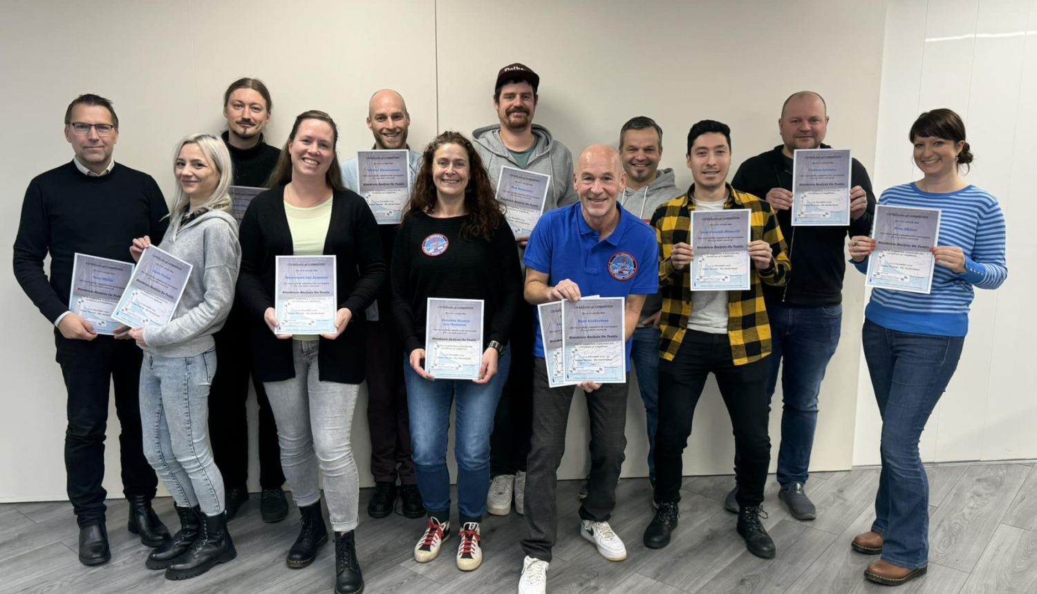 Vairāku cilvēku grupa pozē ar sertifikātiem rokās