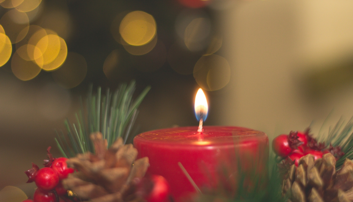 Sarkana degoša svece ar egles zariem apkārt,  čiekuriem un sarkanām ogām